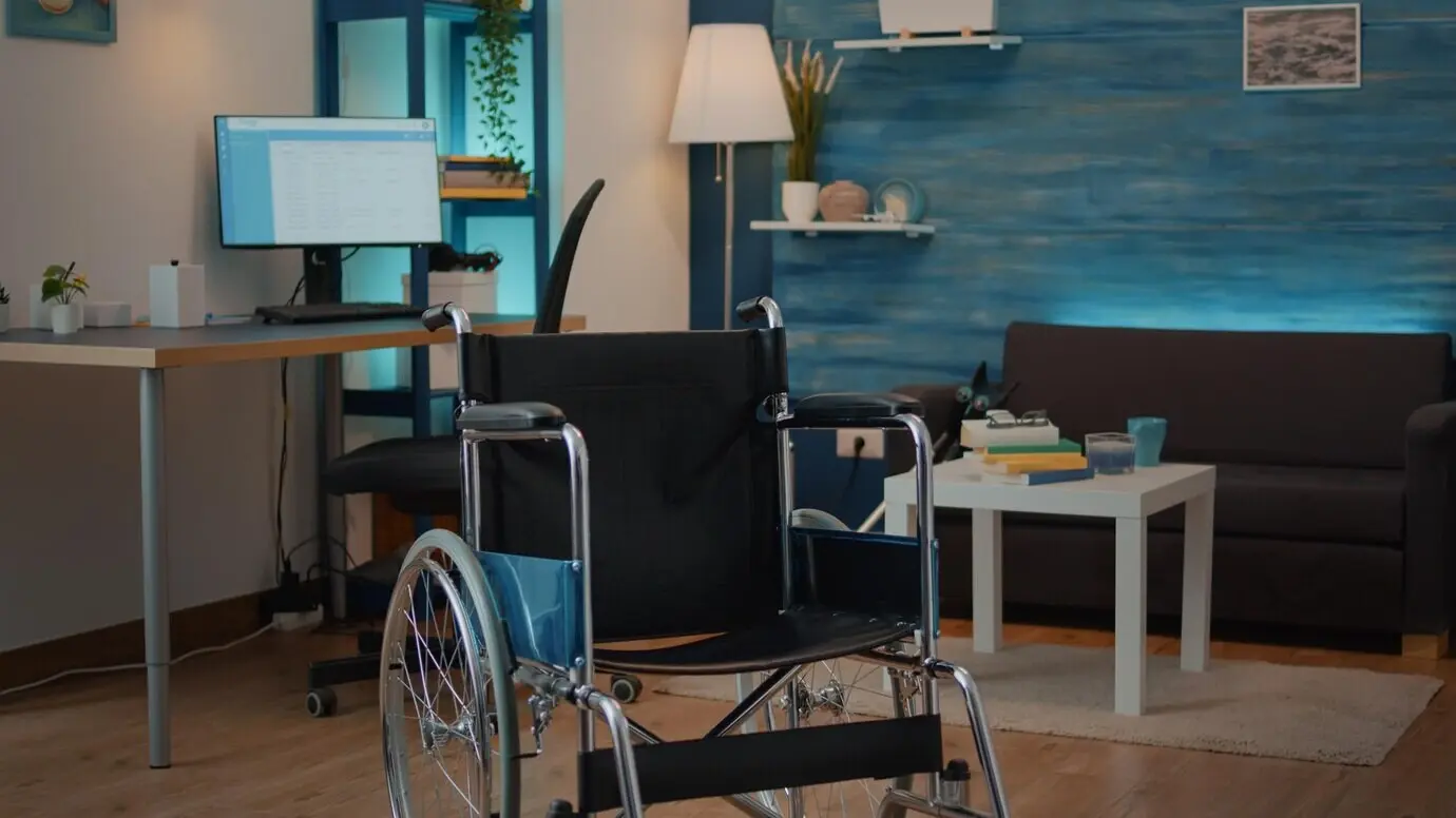 Empty living room with a wheelchair to help with chronic disability and injury. No one present; the transportation device supports the patient and aids accessibility. Physical recovery.